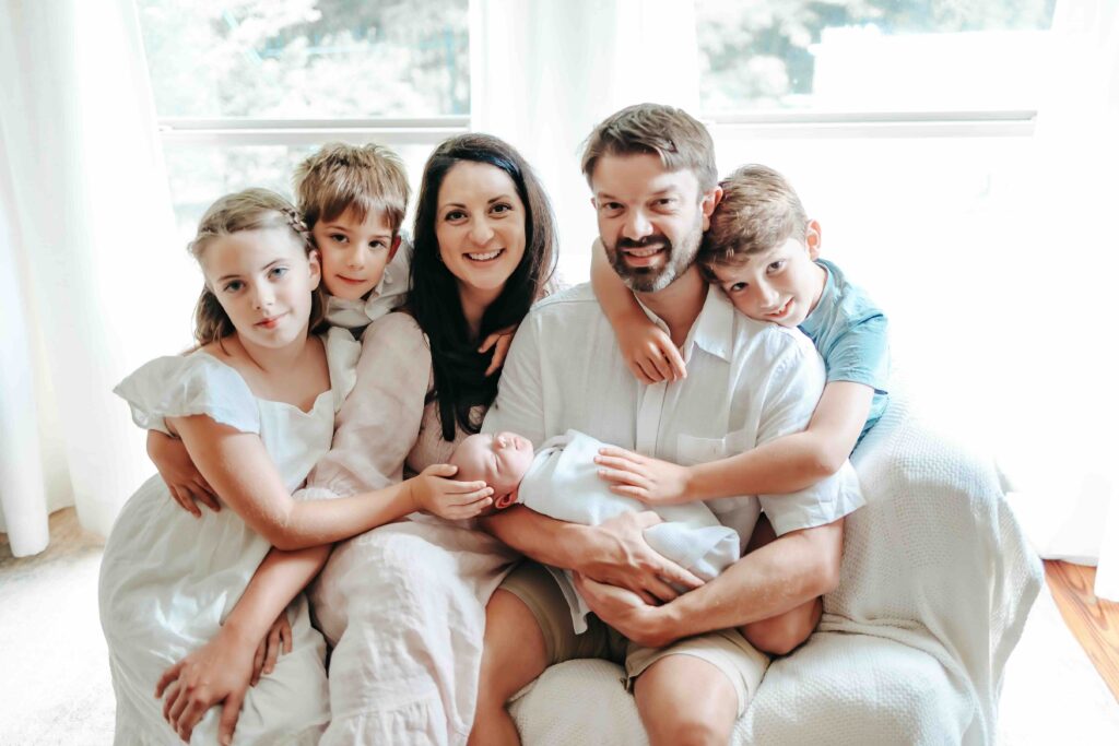 family of six embrace during lifestyle newborn family session